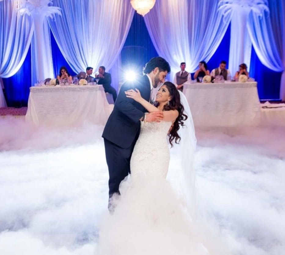 Newlyweds dancing together above a layer of low-lying fog